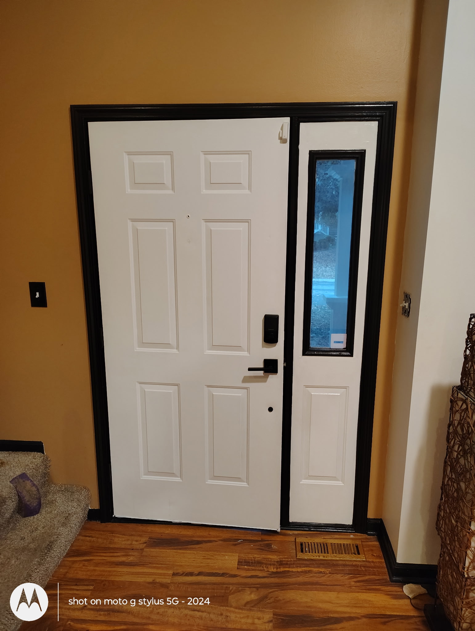 White six-panel entry door with black trim and sidelight