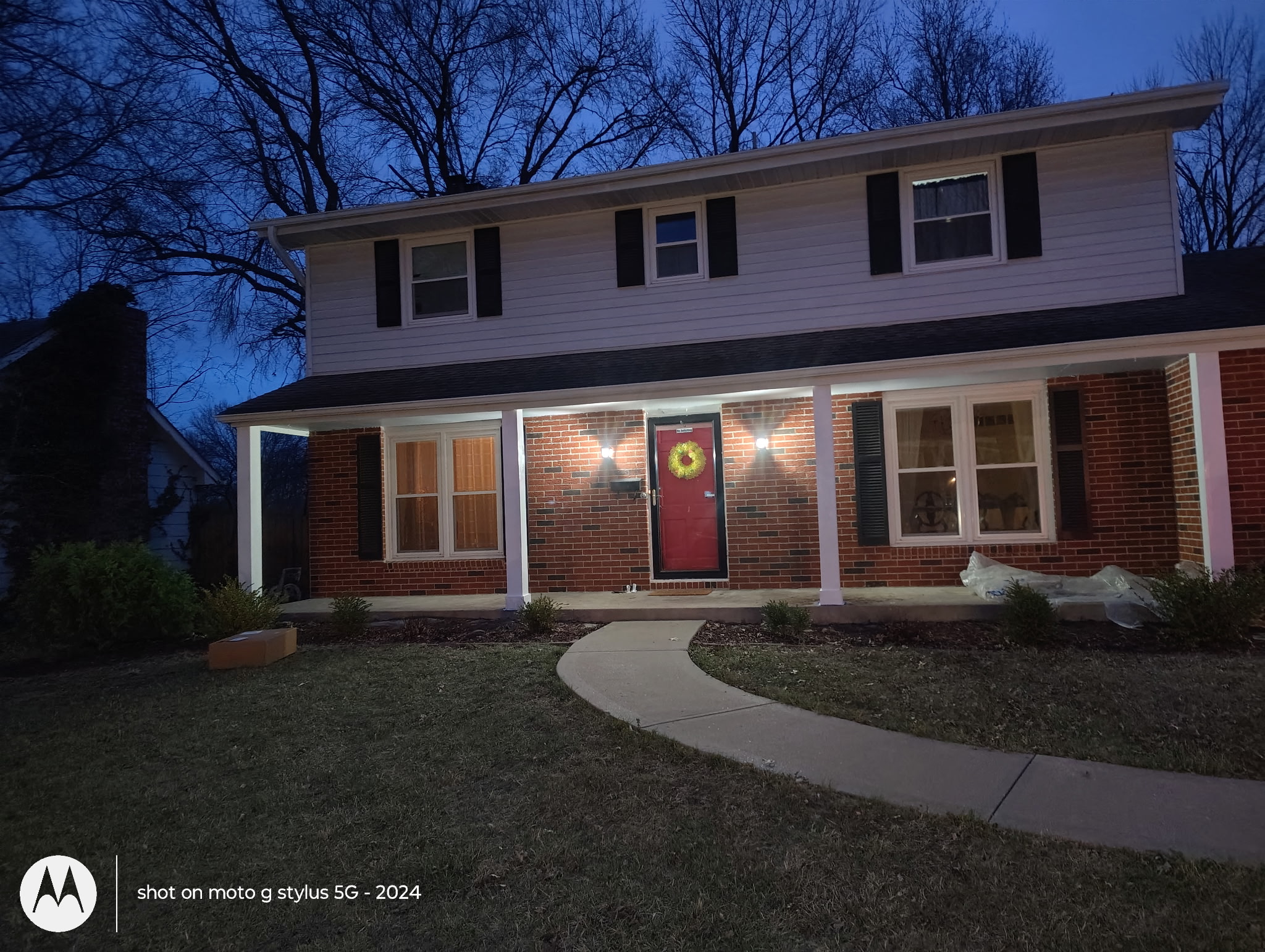 Two-story home exterior with lit porch at dusk