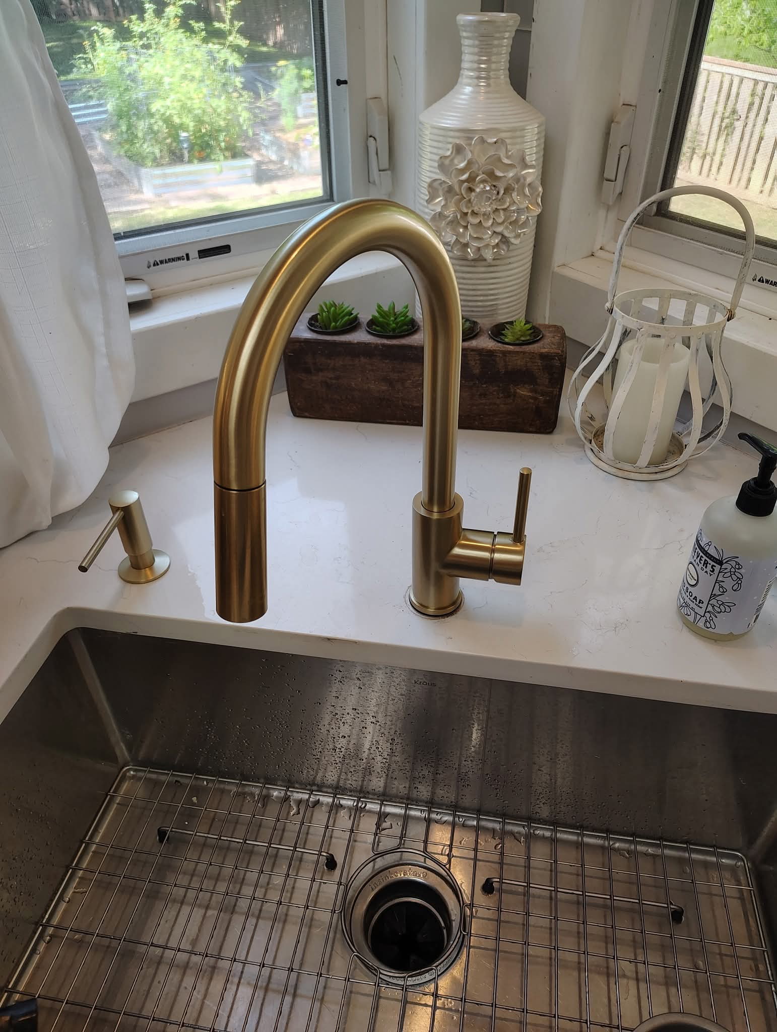 Gold pull-down kitchen faucet installed over a stainless sink